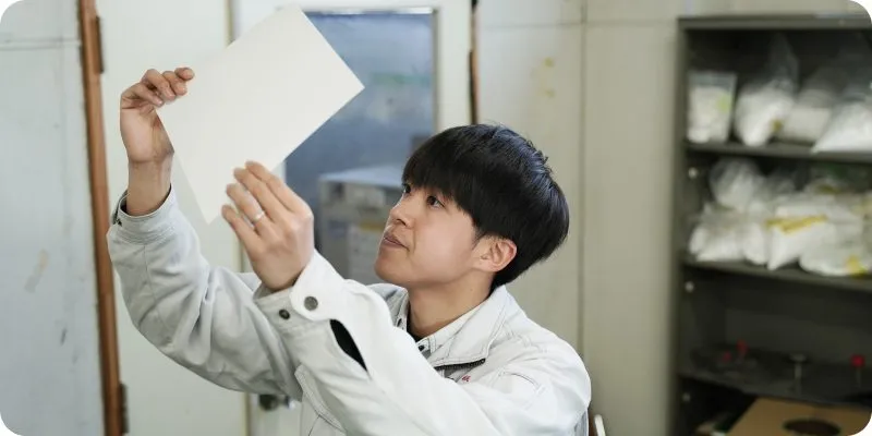試作紙を持って確認する研究開発職社員